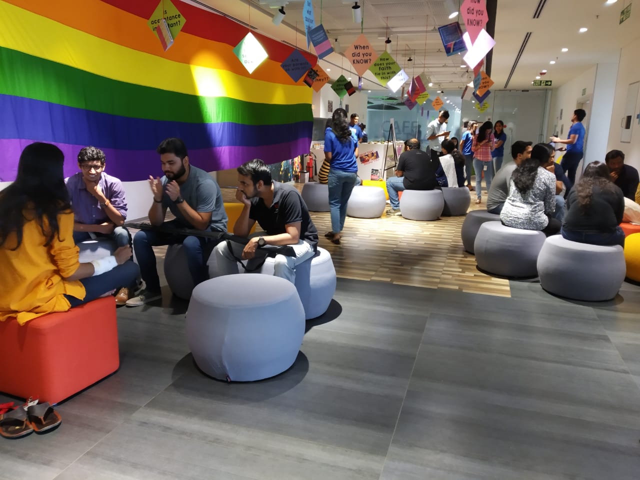 Road to Utopia’s Pride Month workplace session—participants in conversation under a large rainbow flag