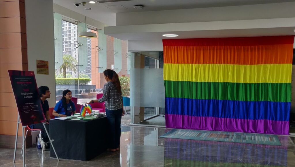 A large pride flag covering a whole wall in a corporate office. and people registering at the booth